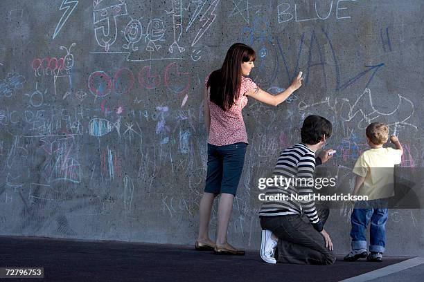mother, father and son (3-4 years) writing in chalk on wall - chalk wall stock pictures, royalty-free photos & images