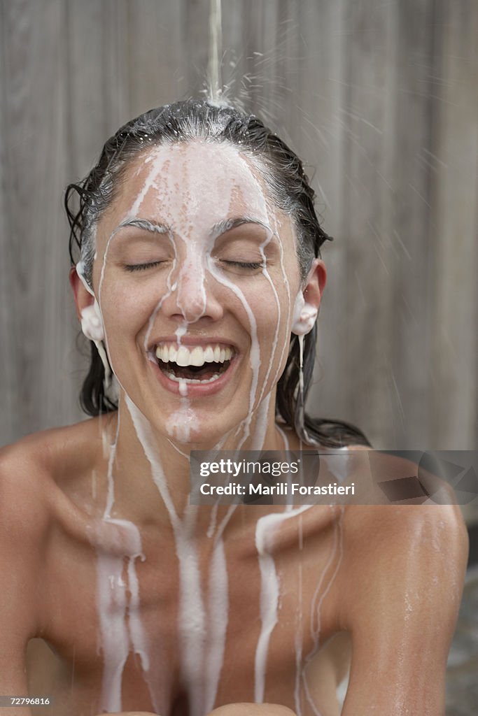 Woman in shower, shampoo running down face