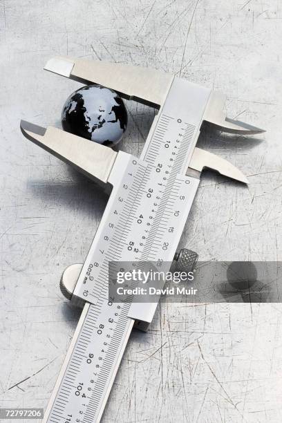 small globe showing europe, asia and north africa in vernier caliper, close-up - vernier caliper stock-fotos und bilder