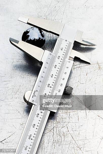 small globe showing antarctica in vernier caliper, close-up - vernier caliper stock-fotos und bilder