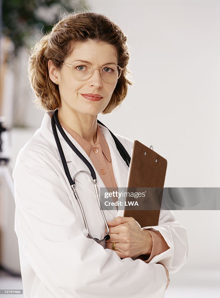 Female doctor holding clipboard indoors, portrait