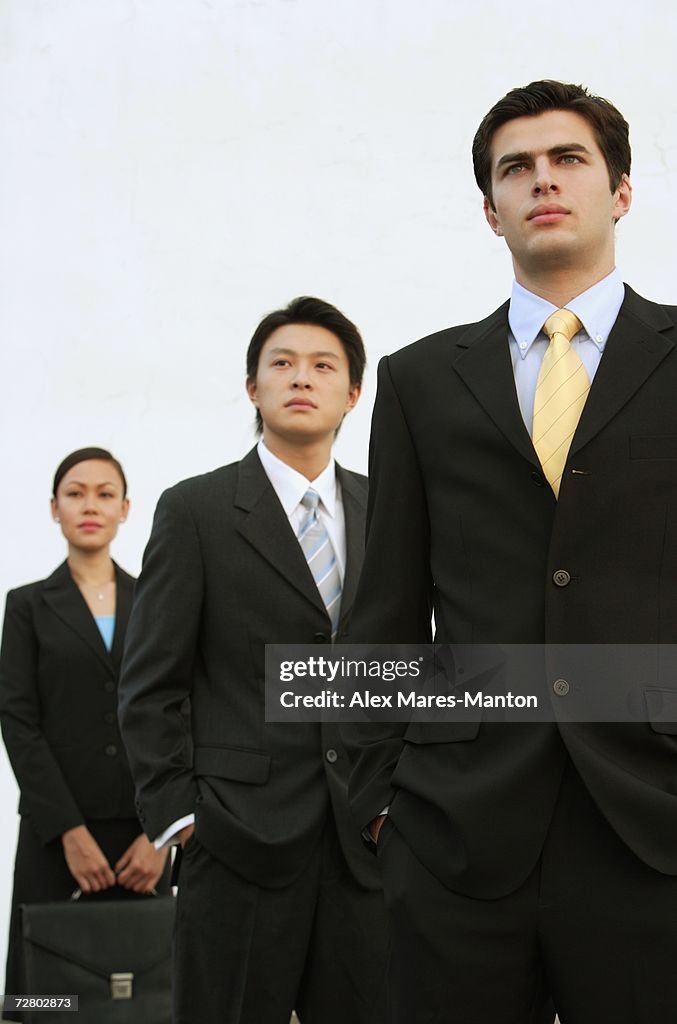 Business people standing in a row, looking away