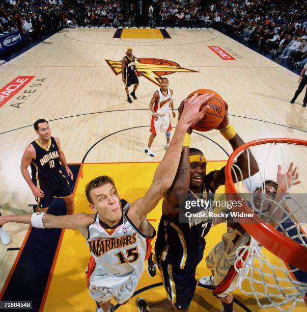 Jermaine O'Neal of the Indiana Pacers goes up for a shot against Andris Biedrins and Troy Murphy of the Golden State Warriors during a game at Oracle...