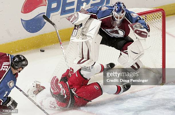 Goaltender Peter Budaj of the Colorado Avalanche leaps into the air to avoid a sliding Erik Cole of the Carolina Hurricanes who was on a collision...