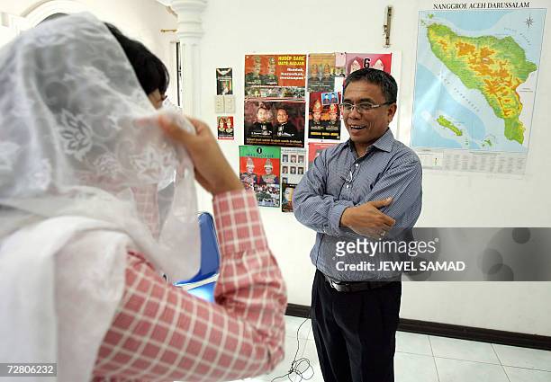 Banda Aceh, INDONESIA: A female journalist adjusts her scarf as she interviews Irwandi Yusuf , the former spokesman of the Free Aceh Movement and a...