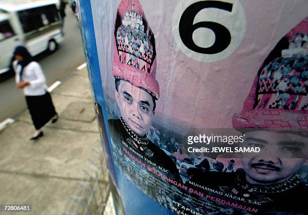 Banda Aceh, INDONESIA: A woman walks past an electoral poster of Irwandi Yusuf , the former spokesman of the Free Aceh Movement and a front running...