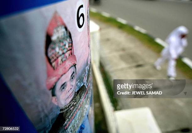 Banda Aceh, INDONESIA: An Acehnese girl in traditional outfit walks past an electoral poster of Irwandi Yusuf, the former spokesman of the Free Aceh...