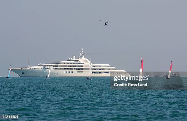 Teams sail in front of yacht "Dubai" as they compete in the Hobie 16 Open Race at the 15th Asian Games Doha 2006 at the Doha Sailing Club on December...