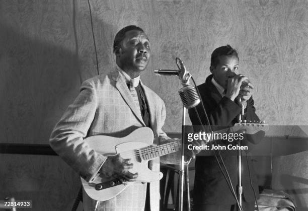 American blues guitarist, songwriter, and singer Muddy Waters and colleague harmonica player Isaac Washington pose for a photo while playing their...
