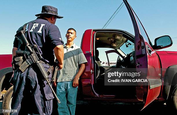 Un agente de la Agencia Federal de Invetigaciones interroga a un conductor en una carretera cerca de Moreloa, estado de Michoacan, el 13 de diciembre...