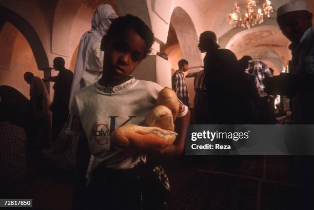 At the end of a mourning ceremony, a boy distributes bread April 2000 in Ghadames, Libya.