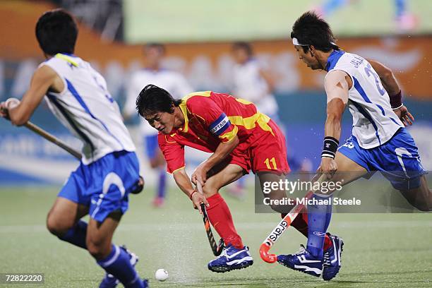 Song Yi of China tries to squeeze a shot inbetween Jang Jong Hyun and Kim Yong Bae of the Republic of Korea during the Men's Hockey Gold Medal Match...