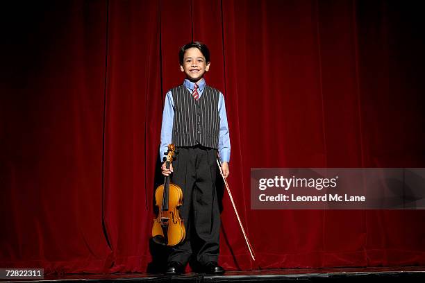 boy (6-7) standing on stage with violin - boy violin stockfoto's en -beelden