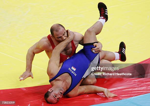 Artur Taymazov of Uzbekistan and Fardin Masoumi Valadi of Iran in action during the Men's Freestyle 120kg medal ceremony at the 15th Asian Games Doha...
