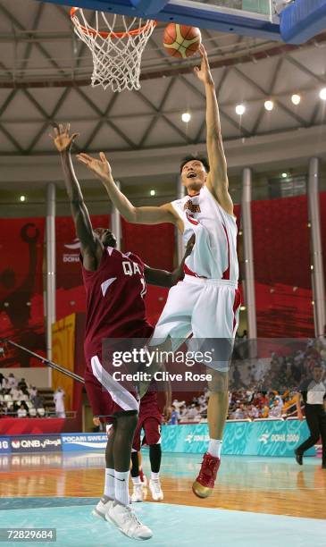 Yi Jianlian of China attempts a shot over Omar Abdelkader Salem of Qatar in the Men's Gold Medal Basketball Match during the 15th Asian Games Doha...