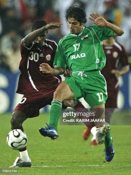 Qatar's Bilal Mohammed Rajab vies with Iraq's Alaa Khashen in the men's football final at Al-Sadd Sports Club during the 15th Asian Games in Doha...