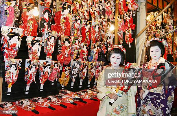 Japanese geisha girls clad in kimonos admire wooden battledores called 'hagoita' at Sensoji temple in Tokyo, during a preview of the three-day annual...