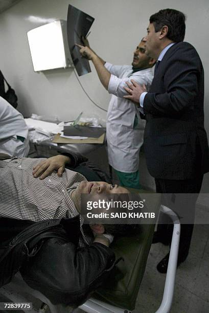 Palestinian doctor looks at an X-ray as he treats veteran French journalist working for the French Liberation daily newspaper Didier Francois at the...