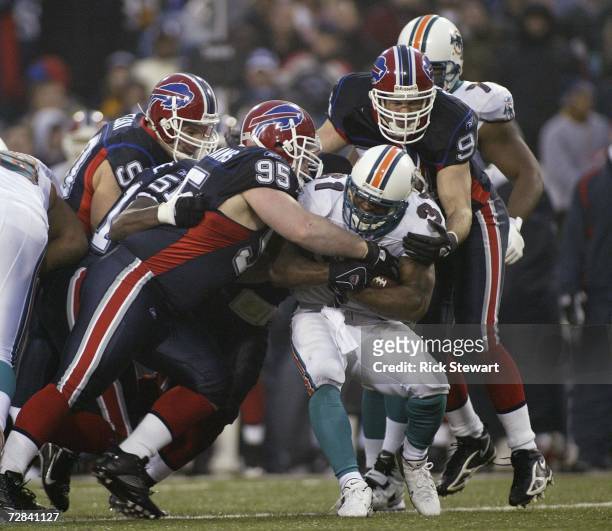 Kyle Williams and Aaron Schobel of the Buffalo Bills tackle Sammy Morris of the Miami Dolphins on December 17, 2006 at Ralph Wilson Stadium in...