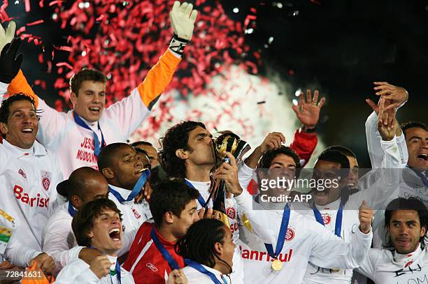 Players of Brazil's SC Internacional celebrate their victory against FC Barcelona as midfielder Fernandao kisses the trophy after their final match...