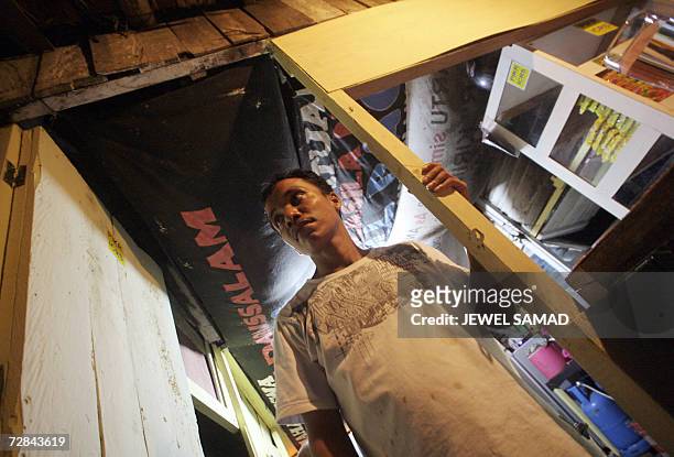 Ibrahim bin Yatim, a former gun smuggler for the Free Aceh Movement , waits at his small food stall in Montasiek, Aceh province, 12 December 2006....