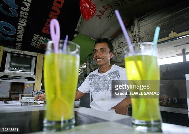 Ibrahim bin Yatim, a former gun smuggler for the Free Aceh Movement , talks with customers at his small food stall in Montasiek, Aceh province, 12...