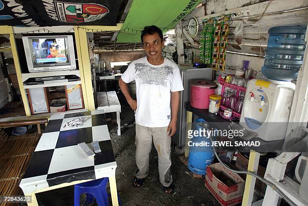 Ibrahim bin Yatim, a former gun smuggler for the Free Aceh Movement , stands inside his small food stall in Montasiek, Aceh province, 12 December...
