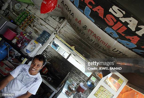 Ibrahim bin Yatim, a former gun smuggler for the Free Aceh Movement , talks with customers at his small food stall in Montasiek, Aceh province, 12...