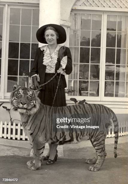 American woman Mrs. Richards, wife of facility co-owner Billy Richards, stands on the terrace of a building with Satan, a tiger , on a chain leash at...