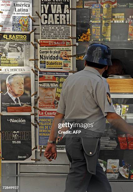 Chilean soldier passes by a kiosco where are displayed the morning papers a day after the death of former Chilean dictator Augusto Pinochet, in...