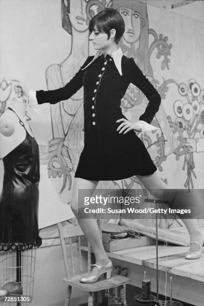 Fashion model stands on a table and a chair as she poses for a portrait in the studio of designer Betsey Johnson, New York, September 6, 1966.