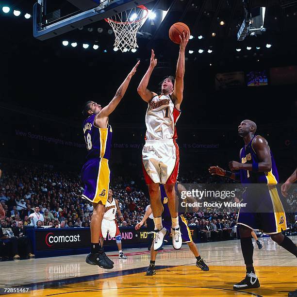 Troy Murphy of the Golden State Warriors takes the ball to the basket against Lamar Odom and Sasha Vujacic of the Los Angeles Lakers during a game...
