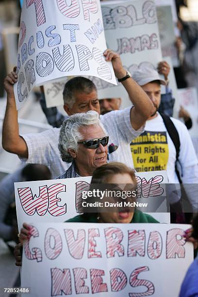 Latino activists hold signs to protest recent immigration raids across the country at a demonstration and news conference in front of the downtown...