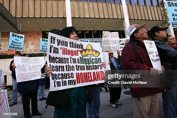 Latino activists hold signs they made as they protest recent immigration raids across the country at a demonstration and news conference in front of...