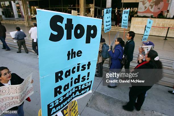 Stop the racist raids signs are held by Latino activists as they protest recent immigration raids across the country at a demonstration and news...