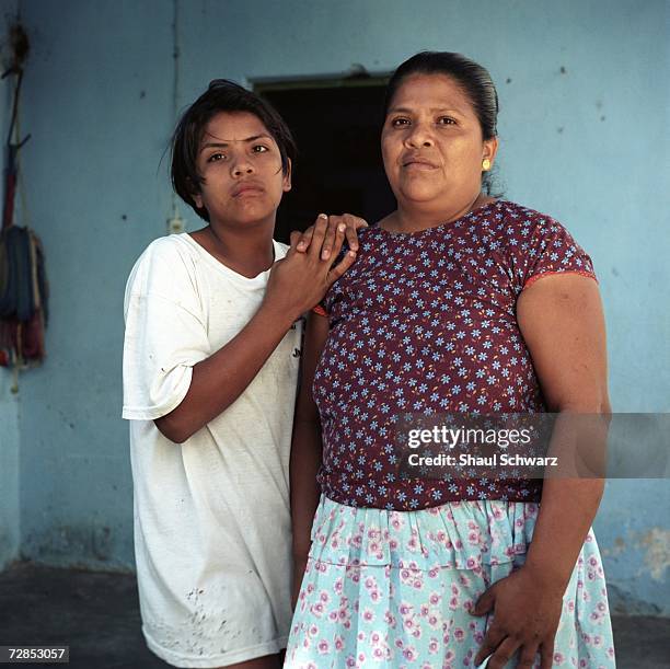 Bidal Aquino Guerra, 13 years old, stands with his mother Anatonia Guerra Aquino at the door in front of his house, October 1, 2002. Bidal stopped...