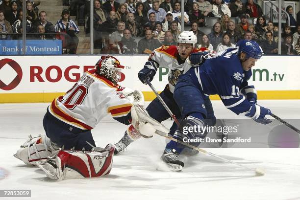 Ed Belfour of the Florida Panthers stops Mats Sundin of the Toronto Maple Leafs as Ruslan Salei of the Florida Panthers looks on during their NHL...