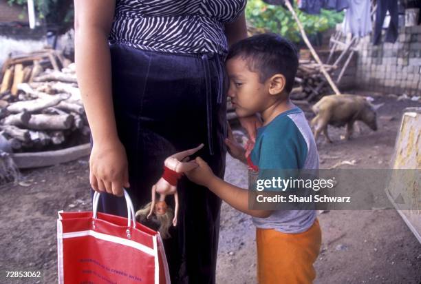 Young boy plays with a barbie doll as he leans on his mother in Juchitan, Mexico, October 1, 2002. In the southern Mexican town of Juchitan of...