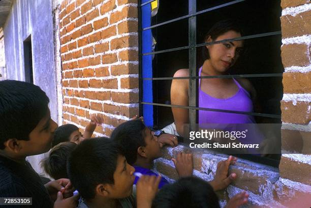 Eighteen-year-old Raul wearing an evening dress, receives attention from kids on the street in Juchitan, Mexico, October 16, 2002. Queen America was...