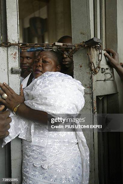 Female party delegate squeezes through a narrow passage created by security operatives in Tafawa Balewa Square in Lagos 20 December 2006, where...