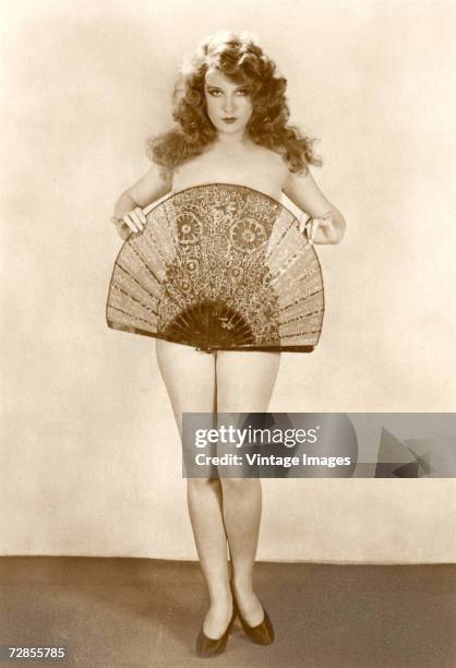 French silent film actress Lili Damita poses naked covered only by a strategically placed fan, 1920s.