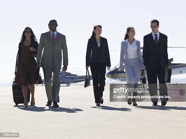 five businesspeople walking near helicopters - five people stock pictures, royalty-free photos & images