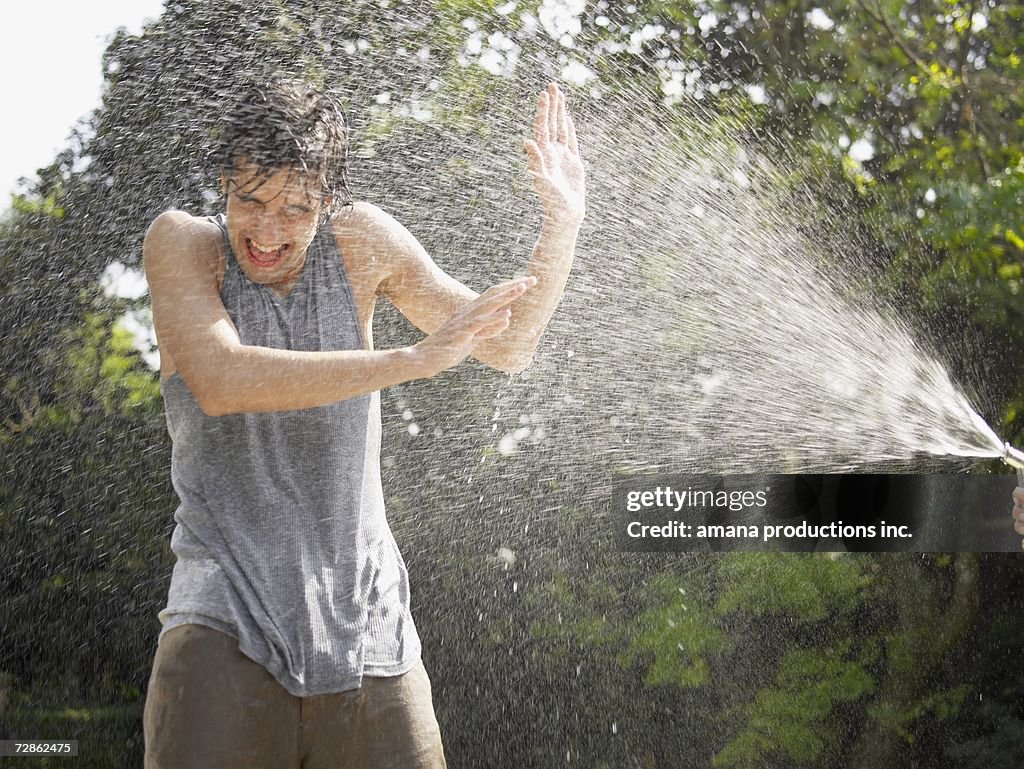 Young man under water spray