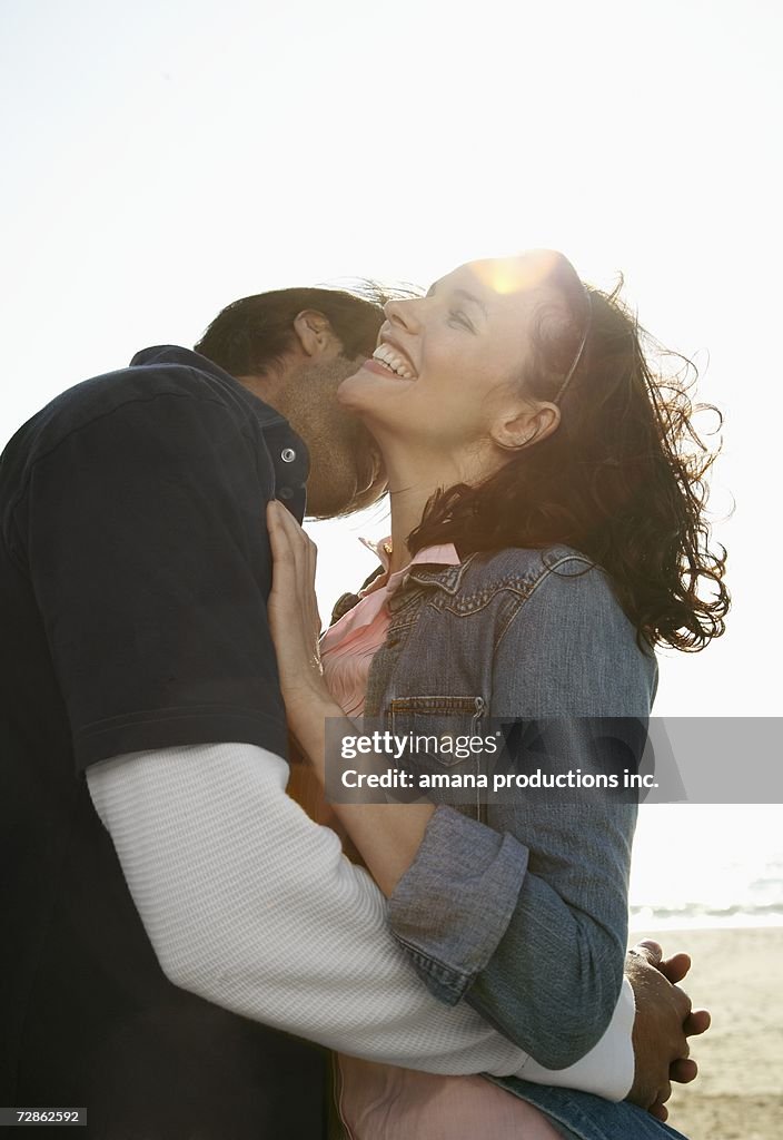 Young couple hugging on beach (lens flare)