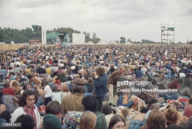 View of rock fans, audience members and young music festival goers watching a group perform on stage at the Weeley Festival, a rock festival held...