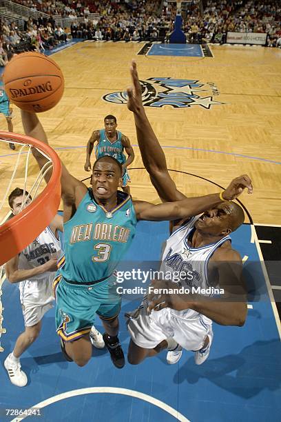 Chris Paul of the New Orleans/Oklahoma City Hornets dunks against Dwight Howard of the Orlando Magic on December 20, 2006 at Amway Arena in Orlando,...