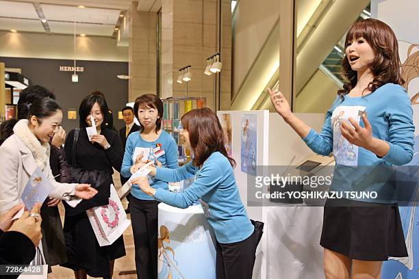 Promotional women along with a 165cm tall humanoid robot "Actroid" introduce French Azzaro perfumes at a Chiristmas gift promotion at Takashimaya...