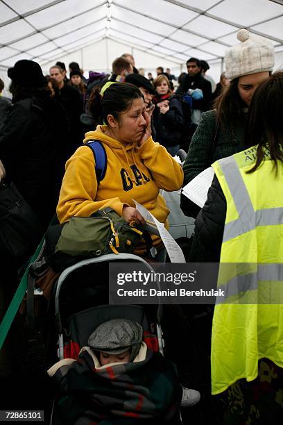 Passenger wipes tears from her eyes as she gets assistance from BAA staff as passengers wait in line in a tent for delayed passengers at Heathrow...
