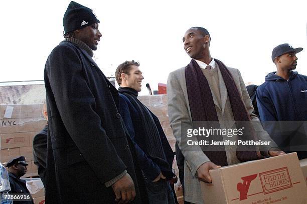 Players Kwame Brown, Luke Walton and Kobe Bryant of the Los Angeles Lakers join Feed the Children to distribute food on 138th Street in Harlem on...