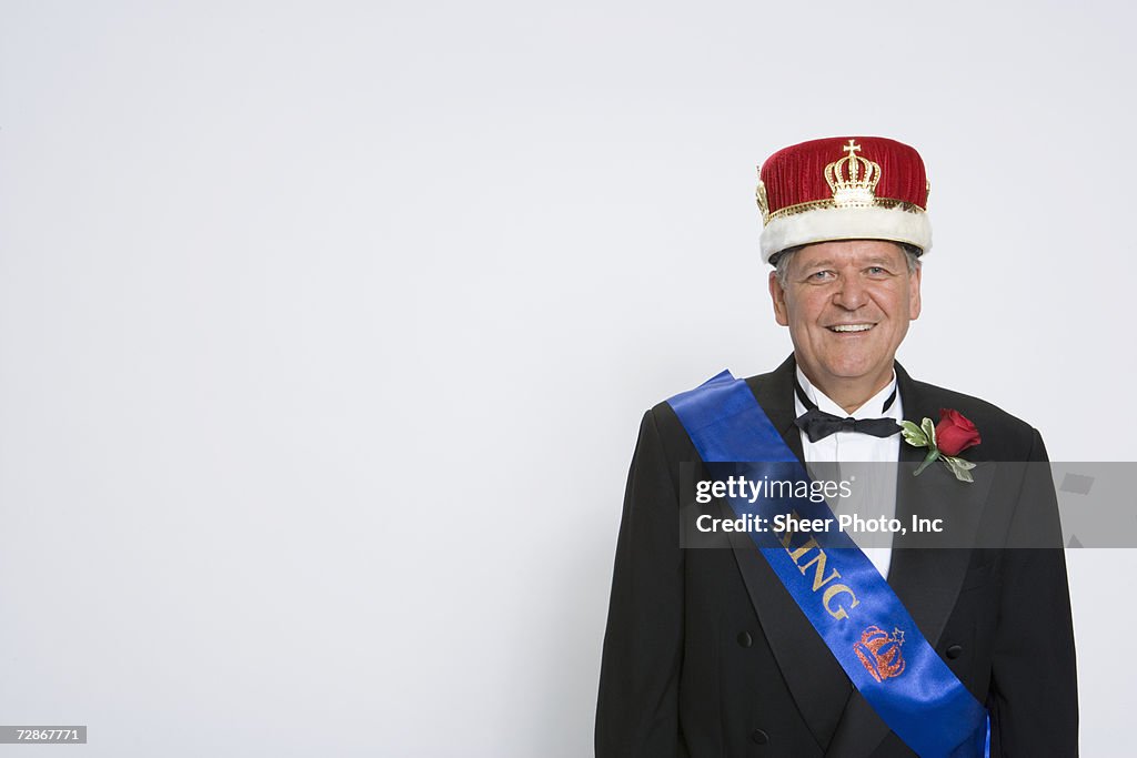 Mature man wearing king's crown and sash, smiling, portrait